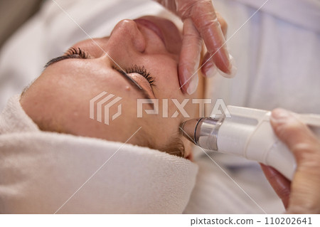 Skin rejuvenation, Aesthetic care, Facial health. In clinical setting, attentive beautician carries out ultrasound treatment focused on facial rejuvenation. 110202641