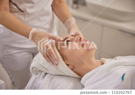perfect skin, head massage, Cosmetology. Beautiful female gets facial massage in beauty clinic, lying on back, getting massage to lift face, beauty concept, skin care, spa concept perfect skin, head massage, Cosmetology. Beautiful female gets facial massage in beauty clinic, lying on back, getting massage to lift face, beauty concept, skin care, spa concept 110202767