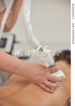 receiving massage, Hardware correction, beauty procedure. Young woman in beauty salon benefitting from beauty services, body shaping, masseur making vacuum roller massage for client, figure correction receiving massage, Hardware correction, beauty procedure. Young woman in beauty salon benefitting from beauty services, body shaping, masseur making vacuum roller massage for client, figure correction 110202826
