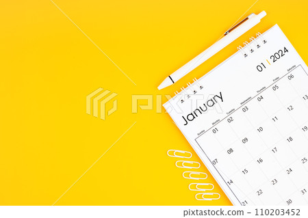 January 2024, Monthly desk calendar for 2024 year and pen with paper clips on yellow color background. 110203452