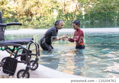 Selective focus off wheelchair background of physical therapist helping senior woman in aqua, old women and mature doing aqua aerobics exercise in swimming pool, Elderly sports, and active lifestyle. Selective focus off wheelchair background of physical therapist helping senior woman in aqua, old women and mature doing aqua aerobics exercise in swimming pool, Elderly sports, and active lifestyle. 110204761