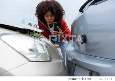 Half Thai African driver check for damage after a car accident before taking pictures and sending insurance. Online car accident insurance claim after submitting photos and evidence to an insurance. 110204775