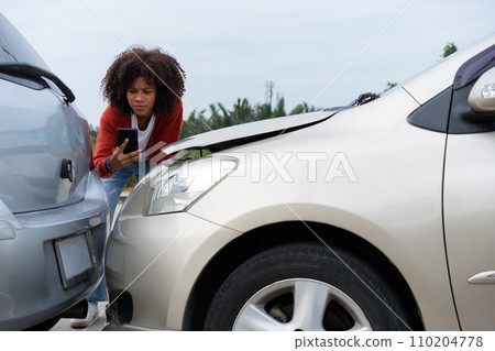 Half Thai African driver check for damage after a car accident before taking pictures and sending insurance. Online car accident insurance claim after submitting photos and evidence to an insurance. Half Thai African driver check for damage after a car accident before taking pictures and sending insurance. Online car accident insurance claim after submitting photos and evidence to an insurance. 110204778
