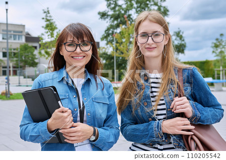 Teacher female and teenage student girl looking at camera together outdoor 110205542