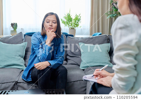 Sad young woman at therapy session with psychologist 110205594