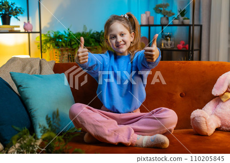 Happy child kid girl looking approvingly at camera showing thumbs up, like positive sign, good news 110205845