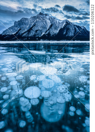 Frozen Abraham Lake with rocky mountains and natural bubbles frost on winter at Kootenay Plains, Canada Frozen Abraham Lake with rocky mountains and natural bubbles frost on winter at Kootenay Plains, Canada 110206122