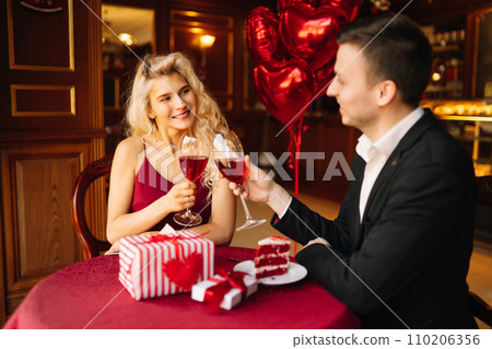 Young couple having a romantic dinner and toasting with glass of red wine. Surprise and love concept Young couple having a romantic dinner and toasting with glass of red wine. Surprise and love concept 110206356