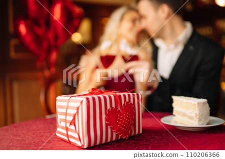 Surprise for Valentine's day. Young couple celebrating Valentine's Day with glass of red wine. 110206366