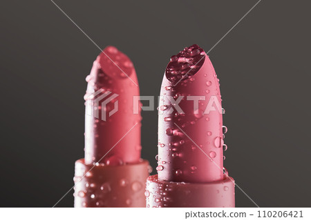 Red lipsticks with water drops on a dark background. 110206421