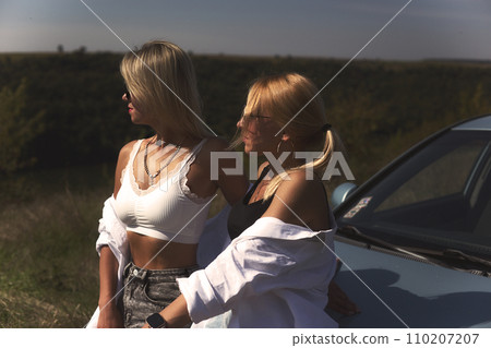 skinny girls are relaxing near a broken car away from the bustle of the city, best friends are free and enjoy the journey. High quality photo 110207207