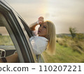 A beautiful girl rides in a car at speed and enjoys the wind from the window, rest from work and bustle, serenity and freedom. High quality photo 110207221