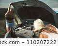 an accident on the road, a car broke down, two beautiful girl models are repairing the motor. Car problem. Friends waiting for service. In the countryside . High quality photo 110207222