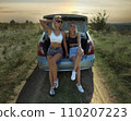 an accident on the road, a car broke down, two beautiful girl models are hitchhiking a car. Showing the thumb up. Problem with the car. Friends waiting for service. In the countryside . High quality 110207223