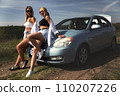 skinny girls are relaxing near a broken car away from the bustle of the city, best friends are free and enjoy the journey. High quality photo 110207226
