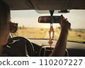 A beautiful girl rides in a car at speed and looks in the rear-view mirror, rest from work and bustle, serenity and freedom. Escape from problems and a chance to be alone. High quality photo 110207227