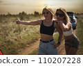 an accident on the road, a car broke down, two beautiful girl models are hitchhiking a car. Showing the thumb up. Problem with the car. Friends waiting for service. In the countryside . High quality 110207228