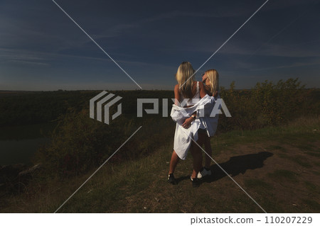 two best friends take a break from work, feel free and enjoy privacy. Blonde sisters in nature look at the landscape. Summer and good weather. High quality photo 110207229