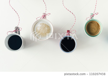 Winter garland with Christmas toy made from cups of coffee hanging on a red white string or twine tied in a bow. White table. Winter Concept. Creative 110207438