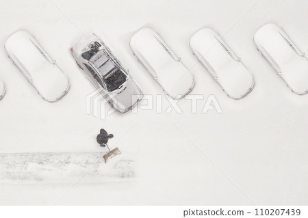 The owner of the car cleans the snow-covered parking space during the snow season. Winter time. 110207439