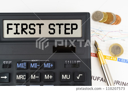 On the table are financial reports, coins and a calculator with the inscription - First Step On the table are financial reports, coins and a calculator with the inscription - First Step 110207573