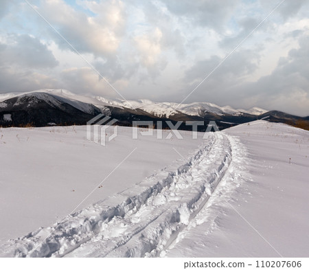 Sledge trace and footprints on winter mountain hill top 110207606