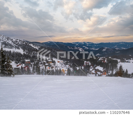 Picturesque winter windy and cloudy morning alps. View of famous Ukrainian Dragobrat ski resort from Svydovets mountain ridge. Picturesque winter windy and cloudy morning alps. View of famous Ukrainian Dragobrat ski resort from Svydovets mountain ridge. 110207646