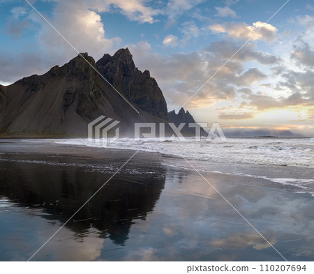 Sunrise Stokksnes cape sea beach and Vestrahorn Mountain with its reflection on wet black volcanic sand surface, Iceland. Amazing nature scenery, popular travel destination. Sunrise Stokksnes cape sea beach and Vestrahorn Mountain with its reflection on wet black volcanic sand surface, Iceland. Amazing nature scenery, popular travel destination. 110207694