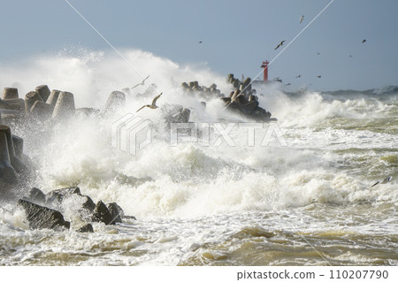 High waves crash against the concrete tetrapods of the harbor breakwater with white splashes High waves crash against the concrete tetrapods of the harbor breakwater with white splashes 110207790