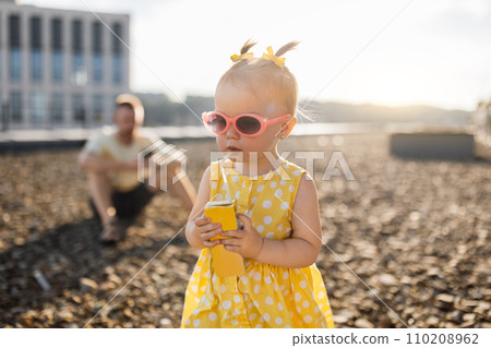 Baby standing and drinking juice while dad sitting behind Baby standing and drinking juice while dad sitting behind 110208962