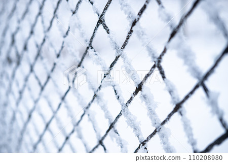 Iron chain-link fence covered with frost and snow close up. selective 110208980