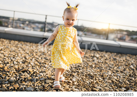 Cute little girl walking on building terrace during sunset 110208985