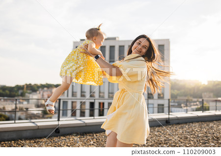 Adult lady holding and spinning with kid on city roof 110209003