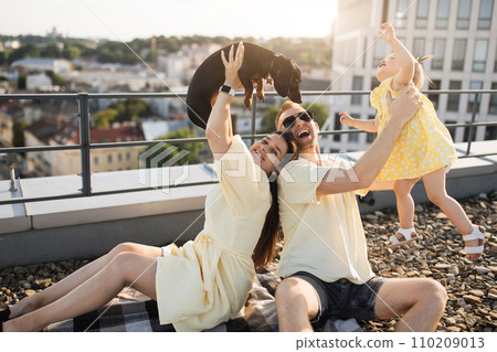 Mom and dad playing with baby and dog on roof of building 110209013