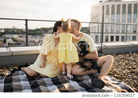 Happy spouses kissing while kid covering faces on roof 110209017