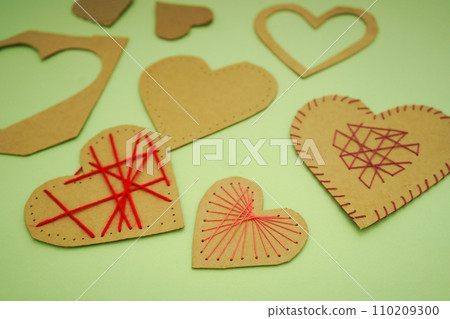 A heart made of cardboard and thread on a green background. Valentine's day ideas are simple for kids. A heart made of cardboard and thread on a green background. Valentine's day ideas are simple for kids. 110209300
