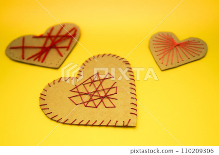 A hearts made of cardboard and thread on a yellow background. Valentine's day ideas are simple for kids. A hearts made of cardboard and thread on a yellow background. Valentine's day ideas are simple for kids. 110209306