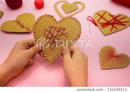 Kids hands hold paper heart. DIY gift for Valentine's Day. Zero waste. Kids hands hold paper heart. DIY gift for Valentine's Day. Zero waste. 110209313