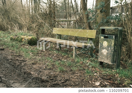 Green trash can next to a park bench in Meerbusch, Germany Green trash can next to a park bench in Meerbusch, Germany 110209701