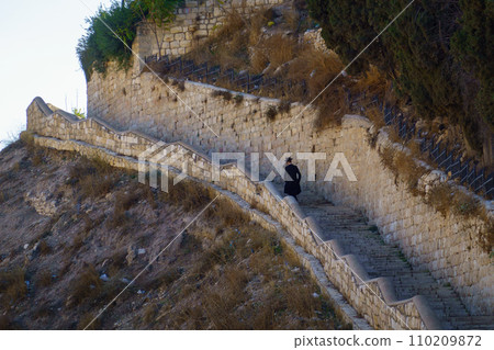 Orthodox Jew in traditional attire descends ancient stone steps in Jerusalem, a moment of quiet reflection. 110209872