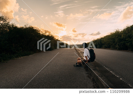 一個人坐在夕陽照亮的路上 110209986