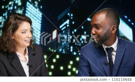 Diverse reporters address breaking news on late night talk show, hosting media entertainment tv program live. Man and woman hosts broadcasters talking about daily events and international topics. 110210688