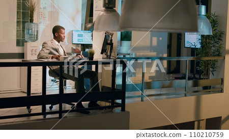Management executive helping worker with auditing project task in office at night, laughing together. Business manager having fun with employee working with data charts during nightshift Management executive helping worker with auditing project task in office at night, laughing together. Business manager having fun with employee working with data charts during nightshift 110210759