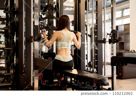 Woman training her back with lat pulldowns at the gym 110212002
