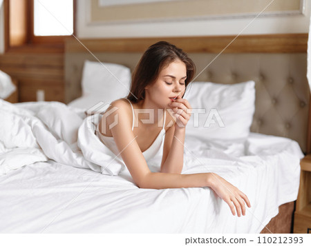 Woman lying on the bed in the morning and looking out the window, cozying up at home on a day off, comfortable underwear, vacation lifestyle with a smile Woman lying on the bed in the morning and looking out the window, cozying up at home on a day off, comfortable underwear, vacation lifestyle with a smile 110212393