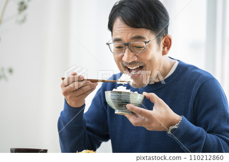 一個50多歲的男人正在吃晚餐 一個50多歲的男人正在吃晚餐 110212860