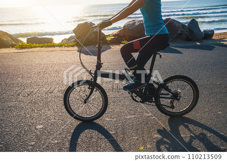 Riding folding bike on sunrise seaside road Riding folding bike on sunrise seaside road 110213509