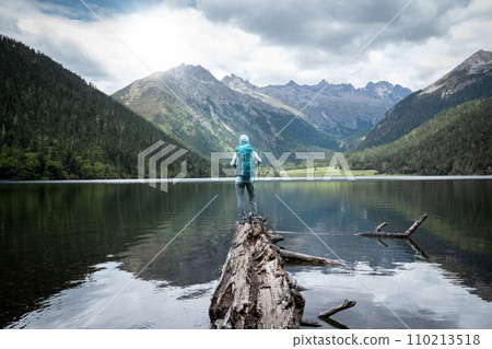 Hiking woman on a one plank bridge in high altitude mountains Hiking woman on a one plank bridge in high altitude mountains 110213518