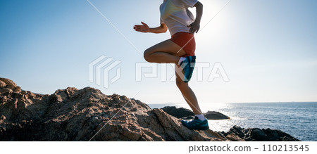 Woman runner running on sunrise seaside rocks 110213545