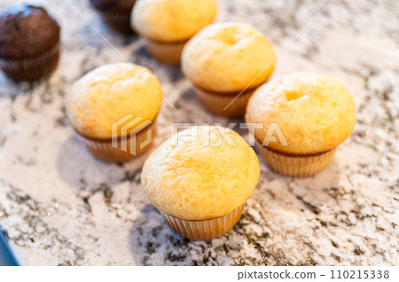 In a cozy kitchen, a batch of vanilla and chocolate cupcakes is being freshly baked as the first step in creating delightful cactus-themed cupcakes, where creative decoration will transform them into 110215338